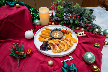 A festive holiday meal beautifully arranged on a decorated table. It features a roast turkey, various side dishes, and holiday decorations, including candles and ornaments. 