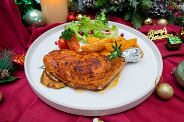 A festive Christmas dish featuring grilled chicken, potato wedges, and a fresh salad, artfully presented on a plate