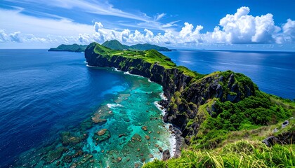 Stunning aerial view of a lush green island peninsula extending into the vibrant blue ocean under a bright sky with white clouds.