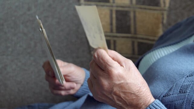 Senior woman reviewing vintage photos. Aging caucasian female deeply engrossed in looking stack photo process. Senior citizen thoughtfully studying historic correspondence with focused attention