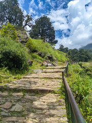 Fast-Flowing Mountain River in the Valley Floor with Large Boulders and Steep Green Slopes Under Blue Sky