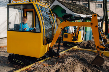 Boy playing with toy excavator at amusement park © Ljustina