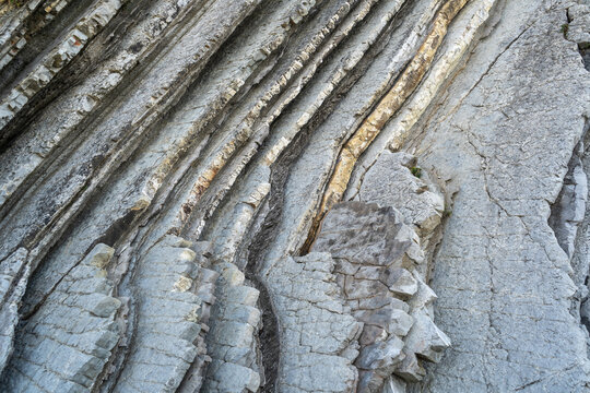Layered rocks, flysch texture background. Sedimentary rock, striations stone pattern