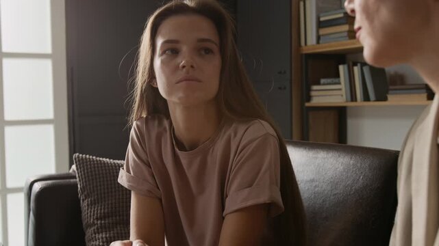 Tilt up view of experienced female counsellor giving psychological support to long-haired young client during consultation