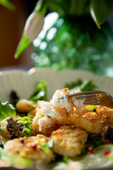 Crispy panko cod cheeks served on fresh gourmet greens with lemon and pink peppercorns - a premium seafood dish for fine dining menus and culinary