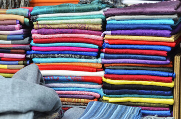 Stacks of Vibrant Colored Fabrics Neatly Arranged in Piles, Showcasing a Colorful Textile Sale Display