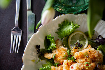 Crispy panko cod cheeks served on fresh gourmet greens with lemon and pink peppercorns - a premium seafood dish for fine dining menus and culinary