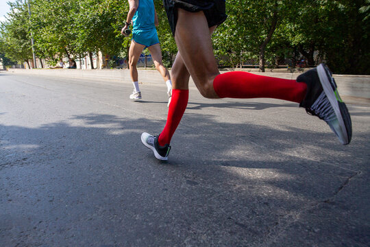 Close-up runner legs in red compression socks running marathon - Powered by Adobe