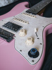 Close-up of a pink electric guitar with pearl pickguard and chrome hardware. This image showcases the details of a stylish pink electric guitar, perfect for music enthusiasts and designers alike