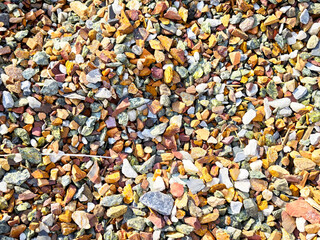 Colorful gravel texture with small stones and pebbles scattered under bright sunlight