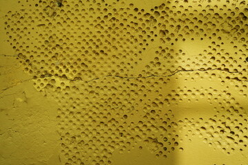 Mur ancien avec alv&eacute;oles rondes peint en jaune.