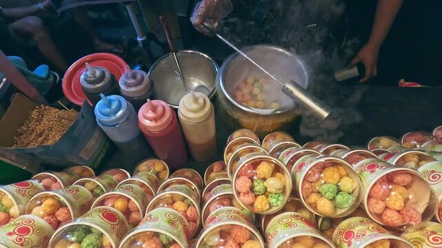 Vendor preparing Dragons Breath dessert which is a frozen dessert made from cereal dipped with liquid nitrogen, at a street food stall in a night market in Dumaguete, Philippines
