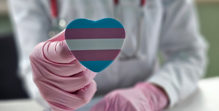 Healthcare professional holding a heart-shaped trans transgender pride symbol while discussing patient