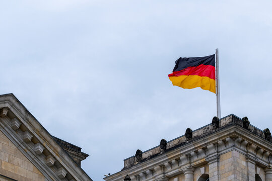 German flag over Berlin architecture expressing national identity, heritage and symbolism within a clear sky, reinforcing government presence and European civic representation