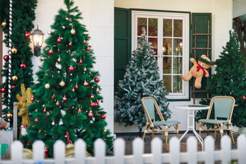 Little teddy bear hanging on the wooden stairs at the window with christmas tree, table and chair for celebrate in christmas holiday