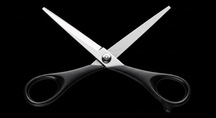 Isolated crossed scissors with black handles and silver blades on a black background studio shot