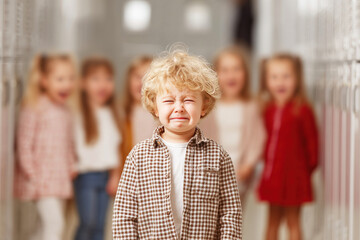 Crying boy in school hallway feels bullied by laughing peers around him