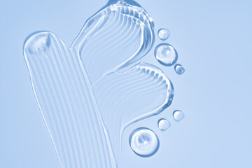 Pure transparent cosmetic gel drops and smears on blue background, skin care glycerin texture. top view
