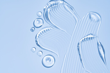 Pure transparent cosmetic gel drops and smears on blue background, skin care glycerin texture. top view