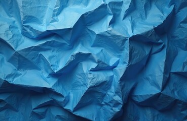 Fototapeta premium Abstract blue crumpled texture background shows many folds, creases. Wrinkled paper surface varying light, shadow, creating depth for design use. Dynamic pattern provides ample copy space for graphic