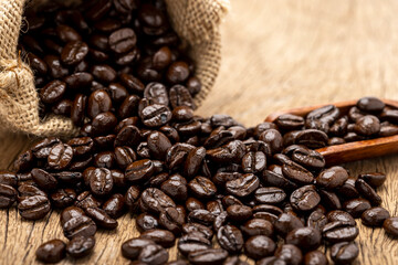 Close up of Coffee beans with Sackcloth bag and spoon on wooden background , Selective focus