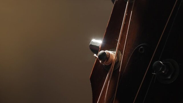 Guitar Headstock Side View: Wooden Neck with Tuning Pegs and Strings Close-up on Classic Acoustic Musical Instrument