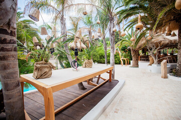 Fototapeta premium Tropical resort lounge with pool, palm trees, cushions, and thatched roofs