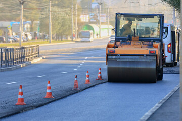 an asphalt paver rolls out new asphalt on the road