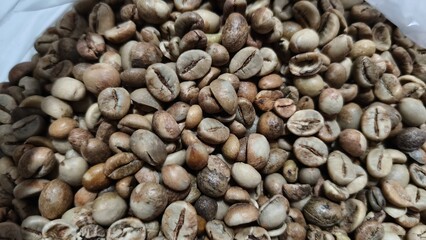 Close-up of raw coffee beans with natural earthy tones, perfect for use in food blogs, product packaging, coffee shop promotions, and agricultural marketing. This detailed texture photo appeals to buy