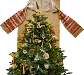 A festive Christmas tree adorned with traditional straw and wooden ornaments, set against a Ukrainian embroidered textile on a transparent background. Perfect for holiday designs.