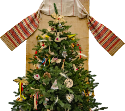 A festive Christmas tree adorned with traditional straw and wooden ornaments, set against a Ukrainian embroidered textile on a transparent background. Perfect for holiday designs.
