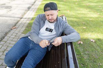 Fototapeta premium Man struggling with opening small package outdoors in park