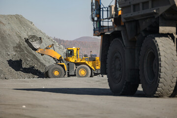 Industry Open pit mine of gold, copper, iron, magnetite ore. Big yellow mining truck at working with heavy industrial wheel loader.