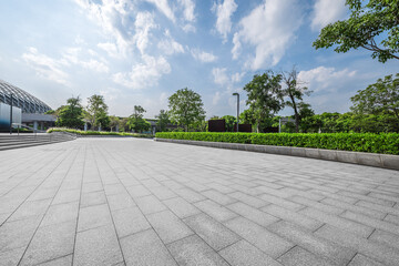 Empty square floor and modern building with green plants.