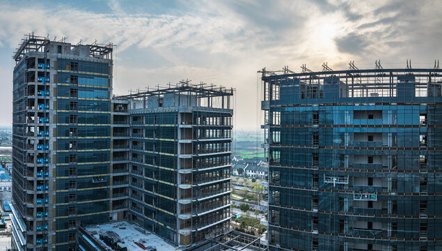 Construction site of modern commercial office buildings with glass windows at sunset.