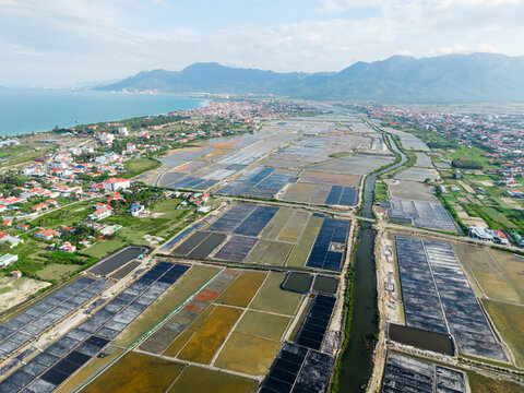 Aerial view of salt fields near coastal village in Vietnam with mountains in background