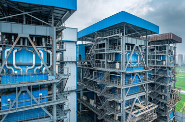 Aerial view of a massive industrial boiler with a complex network of pipes and steel structural framework.