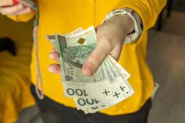 Hand holding several Polish 100 zloty banknotes. Close up image symbolizing cash,