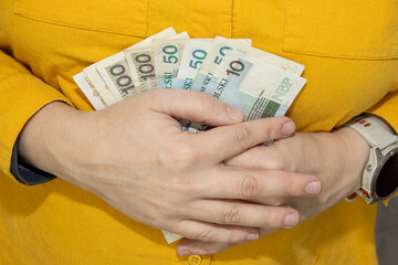 Hands holding a fan of Polish banknotes. Close up view symbolizing savings,