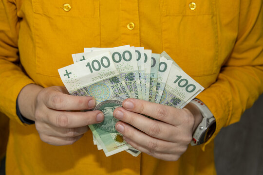 Hands holding a fan of Polish 100 zloty banknotes. Close up image representing wealth, savings