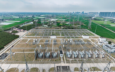 Aerial panoramic view of large electrical substation facility with transformers and power lines in industrial area.