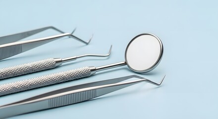Close-up of shiny metallic dental tools arranged on a light blue background for oral health concept and professional dentistry