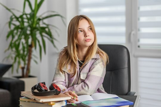 Thoughtful teenage girl studying at desk