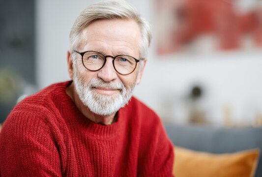Mature man relaxing at home, smiling with confidence while wearing glasses and a warm sweater