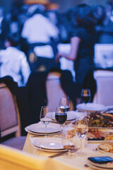 Elegant dining setup at a celebration with fine dishes and wine glasses in a lively event space