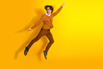 Obraz premium Energetic man in mustard cardigan jumps with joy against a bright yellow background