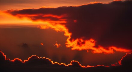 Spectacular close-up of a dramatic sky with dark storm clouds lined in brilliant fiery orange from the setting sun