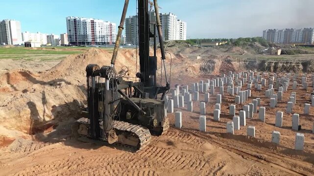 A diesel piling rig is seen driving concrete piles into the ground at a construction site near residential buildings, completing essential foundation work.