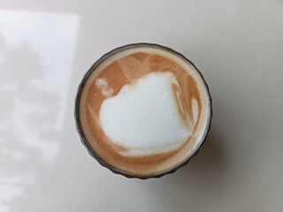 This image shows a cup of coffee with failed foam art, creating an uneven mix of milk and espresso on.