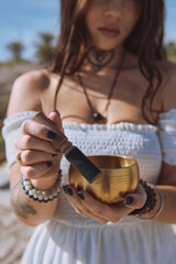 Close up woman begins to play Tibetan bowl with wooden mallet, representing sound healing and meditative focus. Concept of energy of mindfulness and the soothing vibration of inner calm